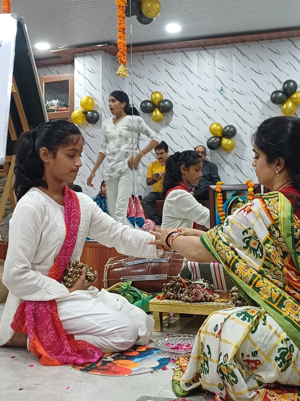 Guru Shivani Patel tying ghungroos on a female student's wrist during Ghungroo Puja